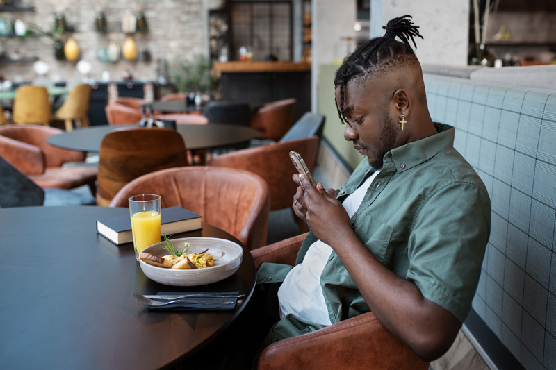 Man sitting at a coffee shop paying on his phone